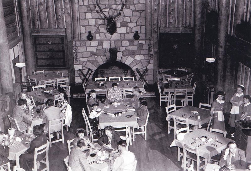 Historic photograph of a dining room at Fuller Lodge with a stone fireplace